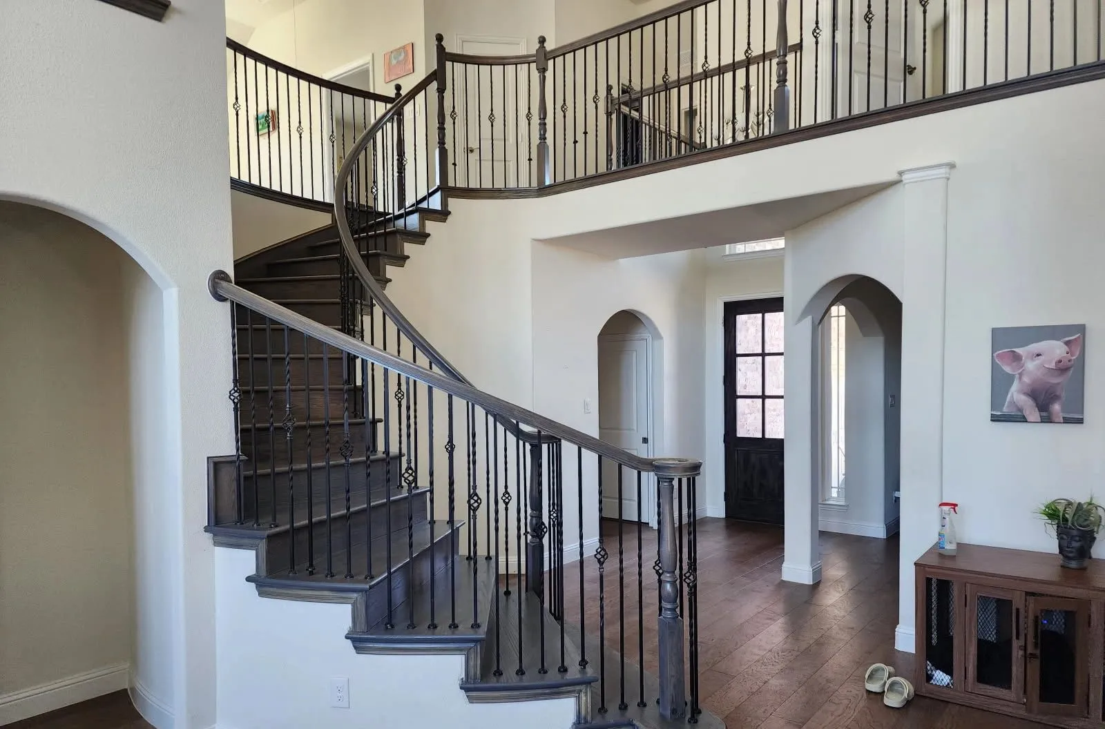 Hardwood flooring and a curved staircase in a two-storey entry hall installed by Artistry Floors in McKinney TX